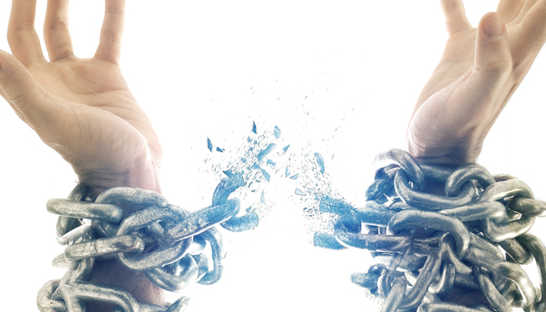 hands breaking out of heavy chains symbolizing freedom and deliverance in Christ